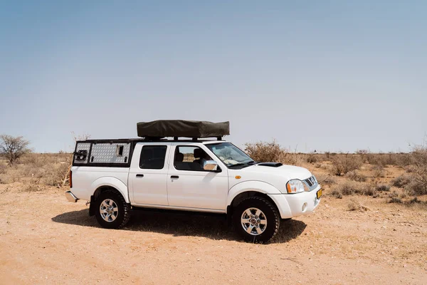 Stan se nachází na střeše pickupu 4x4 auto na osamělé pouštní ulici v Africe — Stock fotografie