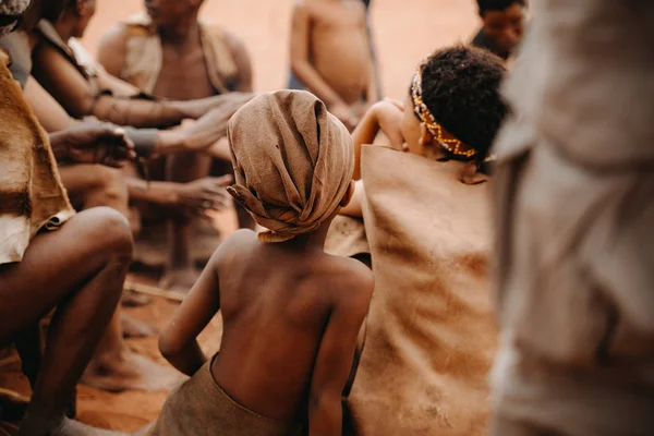 Αφρικανικό παιδί από πίσω στην κοινωνική ομάδα των ανθρώπων που κάθονται στο παραδοσιακό χωριό — Φωτογραφία Αρχείου