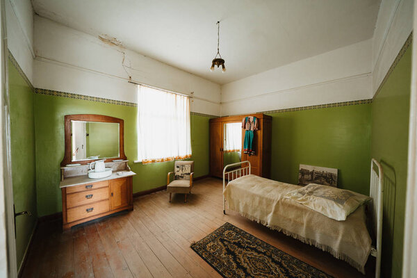 Interior of a colonial green sleeping room with bed and furnitures
