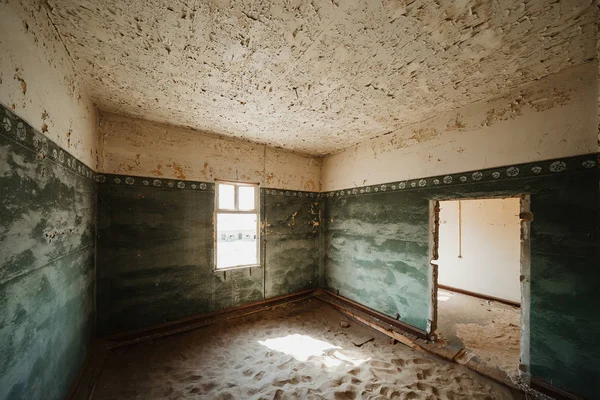 Dune de sable remplissant la maison de ville fantôme abandonnée par des portes et une fenêtre cassée — Photo