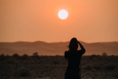 Kadın kamerayla günbatımının fotoğraflarını çekiyor.