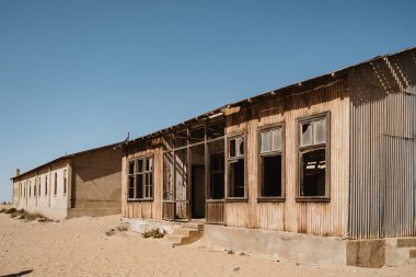 Abandoned buildings left to rot in wild west scenery with desert sand