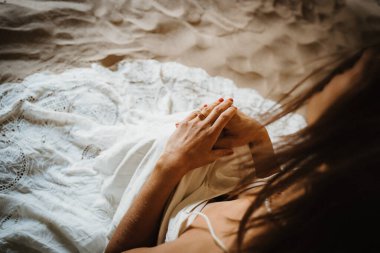 bride with white wedding dress sitting in the sand