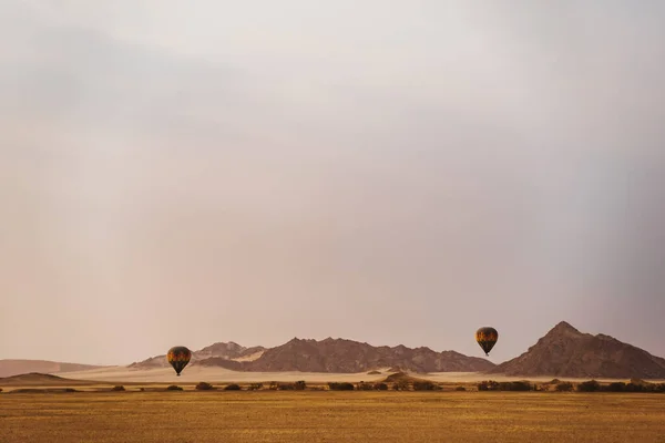 Balony na ogrzane powietrze latające rano na pustyni — Zdjęcie stockowe
