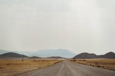Tozlu 4x4 araba Namibya Çölü 'nün ortasındaki yolda.