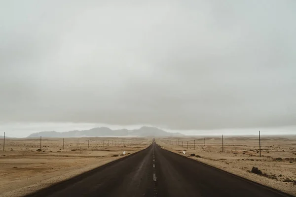 Pylons da eletricidade em montanhas secas do deserto com céu dramático — Fotografia de Stock