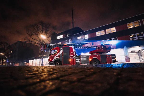 Caserne de pompiers la nuit avec des camions de pompiers répondant à l'appel d'urgence et partant — Photo
