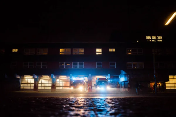 Brandstation på natten med brandbilar som svarar på nödsamtal och lämnar — Stockfoto