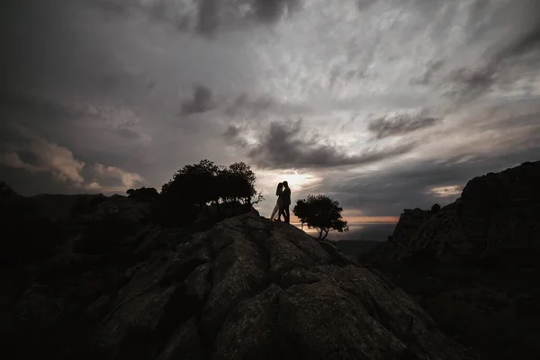 Paar auf dem Gipfel des Berges stehend, Händchen haltend und Sonnenuntergang beobachtend — Stockfoto