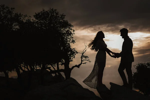 Pareja de pie en la cima de la montaña, tomados de la mano y viendo la puesta de sol —  Fotos de Stock