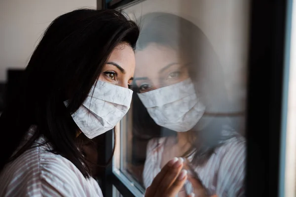 woman wearing selfmade protection mask at window