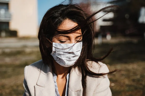 Güneş altında kendini koruyan maske takan bir kadın.