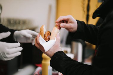 Fast food sosisli sandviç alan bir adamın fotoğrafı.