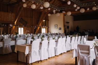 Bir sürü masası olan boş bir düğün salonunun fotoğrafı.