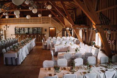 Bir sürü masası olan boş bir düğün salonunun fotoğrafı.