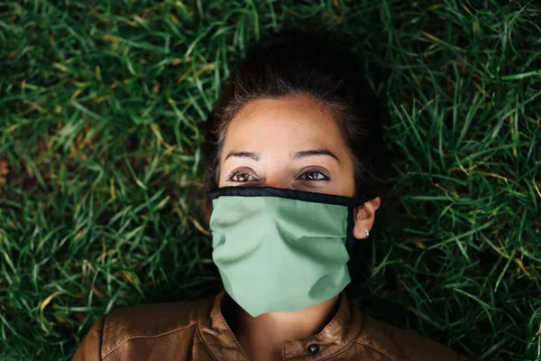 Foto di un volto femminile che indossa una maschera che giace sull'erba — Foto Stock