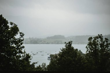 Tekneli bulutlu bir gölün fotoğrafı.