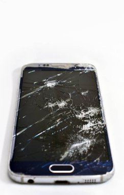 Kulaklık ve kırık ekranlı harap cep telefonu.