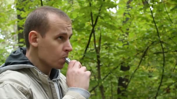Мужчина курит электронные сигареты на открытом воздухе — стоковое видео