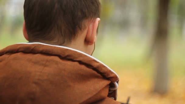 Zadní pohled na člověka se sluchátky na uších drží mobilní chytrý telefon — Stock video