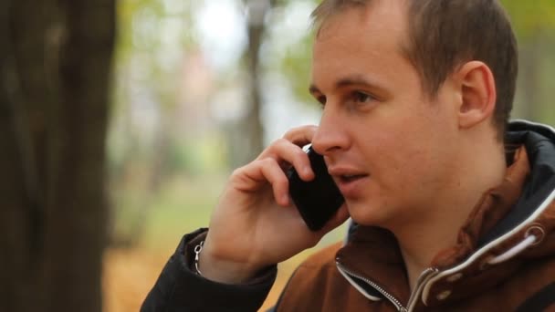 Молодой человек разговаривает по телефону — стоковое видео