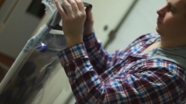 Genç adam ütü masasını açıyor.