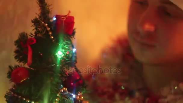 Hombre endereza su hermoso pequeño árbol de Navidad brillante — Vídeos de Stock