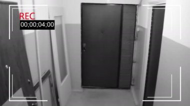 Maskeli adam kapıyı kırıyor ve elinde silahla koridorda koşuyor.