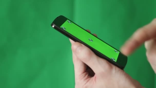 Hombre y un teléfono inteligente de pantalla verde. Fondo verde — Vídeos de Stock