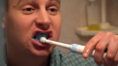 Genç adam sabahları dişlerini fırçalıyor.