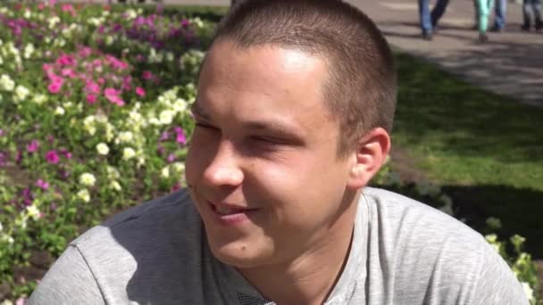 Gros plan d'un jeune homme souriant regardant la caméra qui change les expressions faciales. Homme fier et satisfait avec t-shirt regardant la caméra — Video