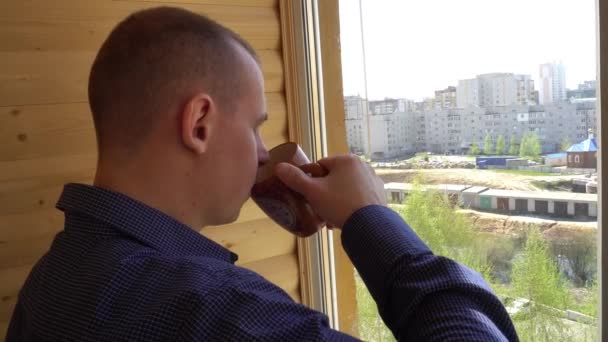 Smutný, deprimovaný muž pije čaj u okna. — Stock video