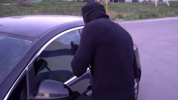Ladrão com um pé de cabra perto da porta do carro — Vídeo de Stock