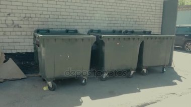 Beyaz tuğla duvarın önünde, ayakta dumpsters