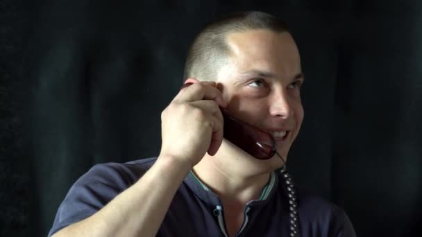 Junger Mann telefoniert im Haus. schwarzer Hintergrund — Stockvideo