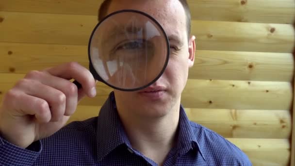 En nyfiken man tittar på kameran med en förstoringslins en detektiv privatdetektiv stora ansikte — Stockvideo