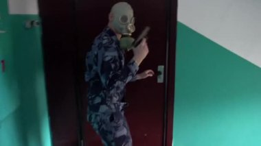 Askeri üniforma giymiş, gaz maskesi takmış bir muhafız binaya girmişti.