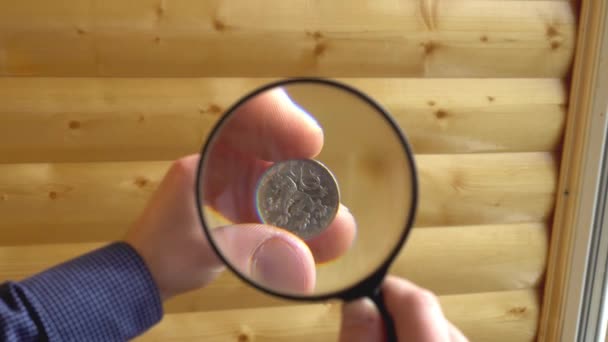 Numismatist considers old coins through magnifying glass — Stock Video