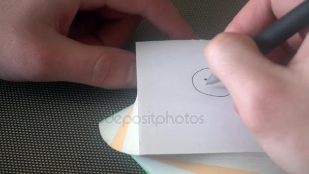 La mano del giovane disegna un volto triste, poi sbarrato, strappa la pagina e disegna un volto sorridente — Video Stock