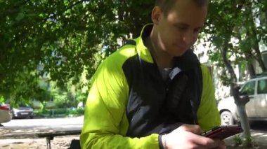 genç adam telefonda, yeşil ağaçlar arka planda çalmaya