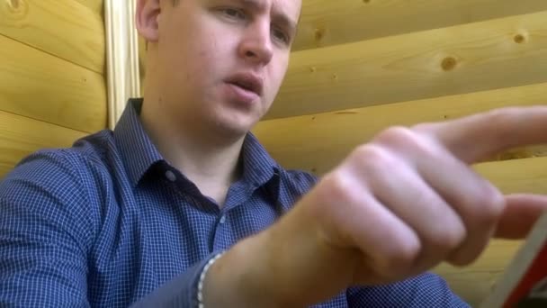 Fiatal üzletember újságot olvas, miközben beszél, az üzemeltetőnek — Stock videók