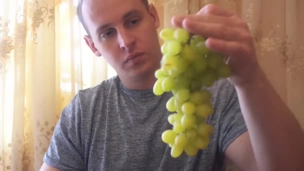 Young man holding green grapes in his hands — Stock Video