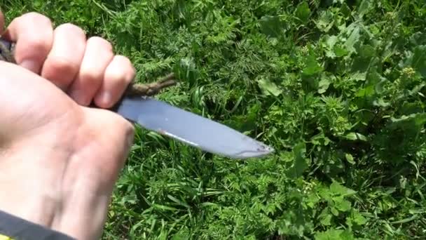 Нож в руке на фоне зеленой травы — стоковое видео