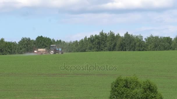 Long shot of a tractor working in a field, compressing the grass in russia, full HD — стоковое видео