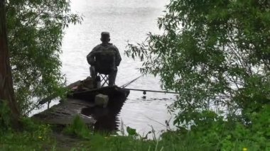 Kursk, Rusya Federasyonu - 28 Mayıs 2017: bir balıkçı bir bekçi şeklinde kıyıda oturur ve bir balık yakalıyor
