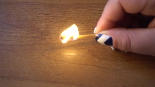 Mano femenina sosteniendo una cerilla ardiente sobre la mesa — Vídeo de stock