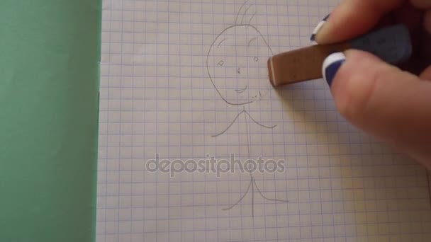 Жіноча рука стирає маленького чоловіка в ластик зошита — стокове відео