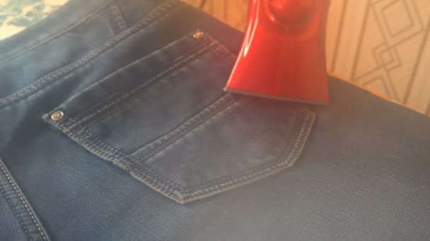 Man steaming denim fabric on ironing table — Stock Video