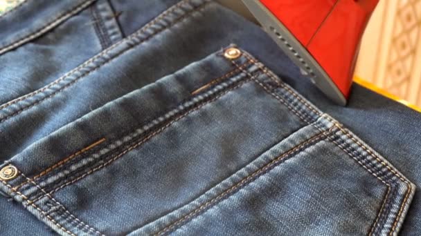 Man steaming denim fabric on ironing table — Stock Video