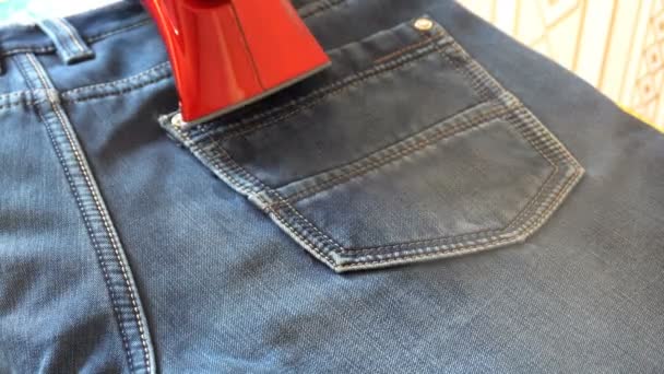 Man steaming denim fabric on ironing table — Stock Video